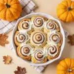 Freshly baked sourdough pumpkin cinnamon rolls topped with creamy glaze on a white plate